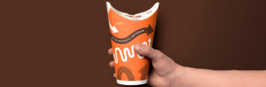 person holding A&W lidless and compostable cup with brown background
