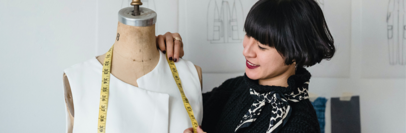 Fashion-designer-taking-measurements-from-mannequin