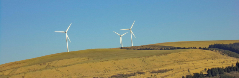 three-white-windmills-on-green-field-under-blue-sky