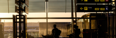 Person sitting in waiting area of an airport and looking out the window.