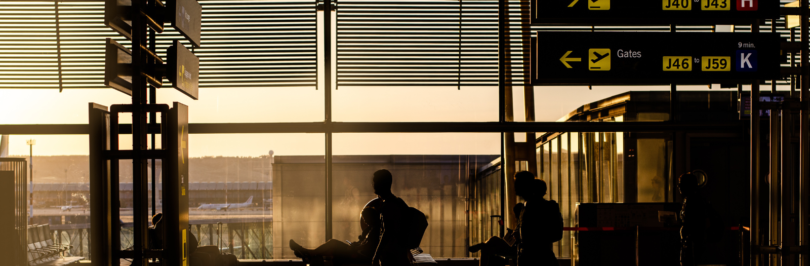 Person sitting in waiting area of an airport and looking out the window.