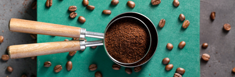 ground coffee on a grinder item surrounded by coffee beans