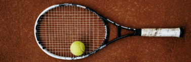 A tennis racket with a ball on top of it