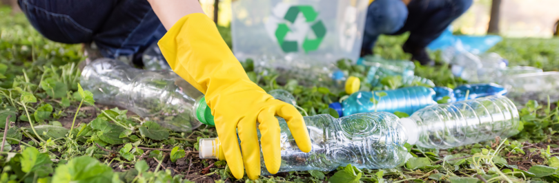 Two youth picking up plastic bottles to recycle