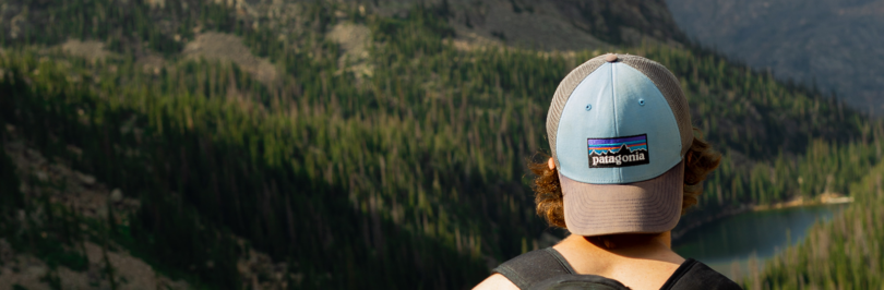 Person wearing Patagonia hat while sitting on a rock looking out to mountains