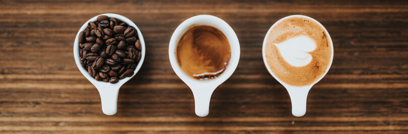 image of three cups containing coffee beans, espresso and cappuccino