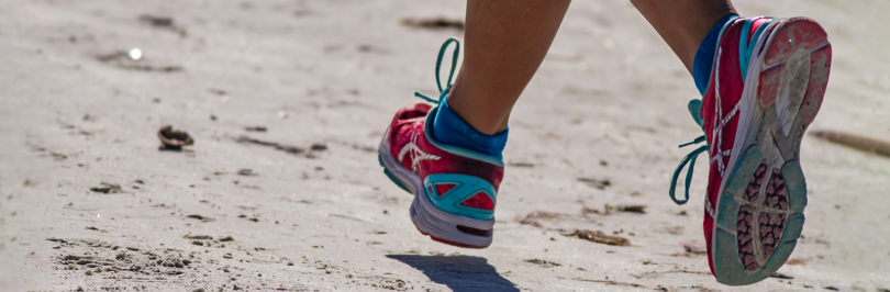 Person running on beach with running shoes