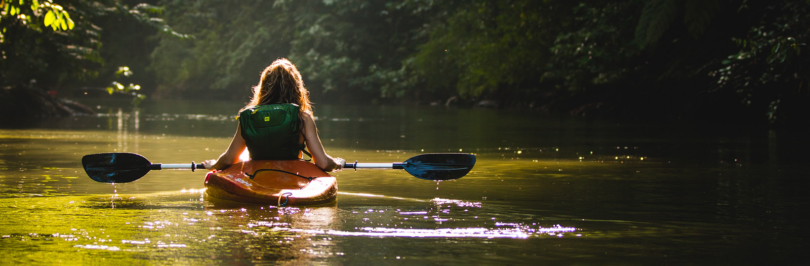 Person on kayak on body of water holding paddle