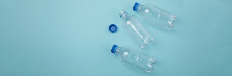 Three empty plastic water bottles lying on blue background