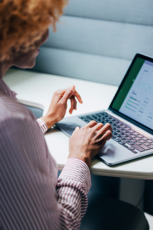 A professional engaging with technology while analyzing financial data on a laptop in a modern workplace. The image highlights focus and productivity in a business environment.