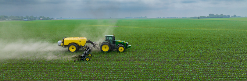 Farming machine spreading fertilizer on field