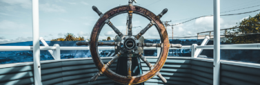 Wooden ship helm on blue boat