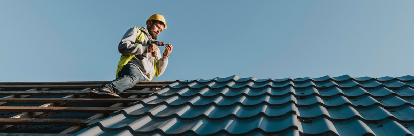 Construction person working on roof with shingles