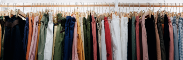 Assorted colour clothes hanging on wooden wall rack