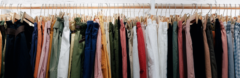 Assorted colour clothes hanging on wooden wall rack