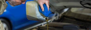 mechanic pouring oil into car engine