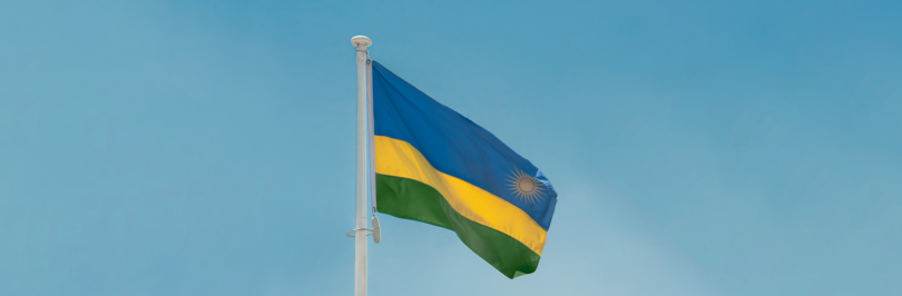 Rwandan flag on flagpole with blue skies