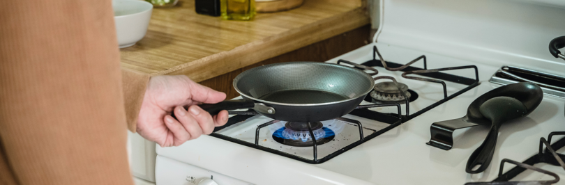 Person using frying pan on gas stove