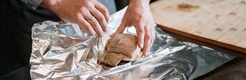 person wrapping item in aluminum foil