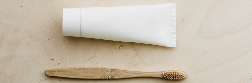 toothpaste tube and wooden toothbrush on table