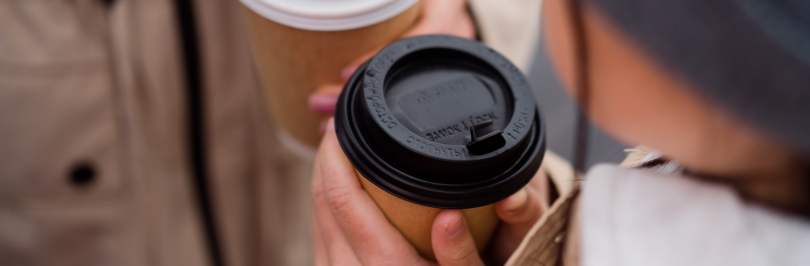 People holding coffee cups with plastic lids