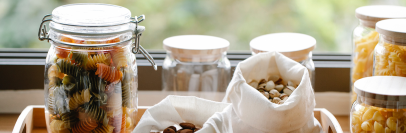 Reusable containers and bags being used to store dried pasta and nuts