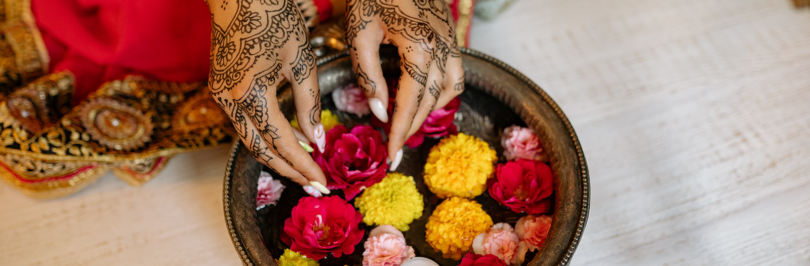 Hands with mehndi putting the colorful flowers on the water
