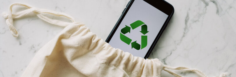 photo of a cell phone with a recycling logo placed within a reusable bag