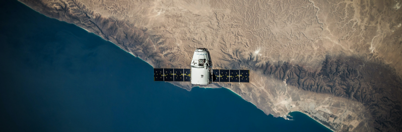 Birds-eye view of a satellite over land and the ocean