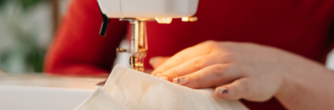 Person guiding fabric into a sewing machine