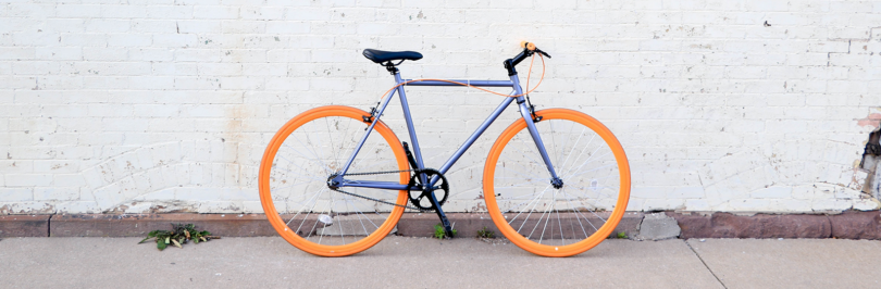 Bicycle with orange tires against a white wall