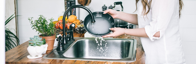 Person washing a plate in kitchen