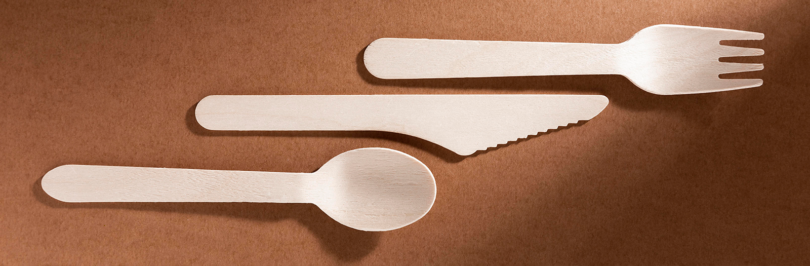 Compostable fork, knife and spoon on brown background